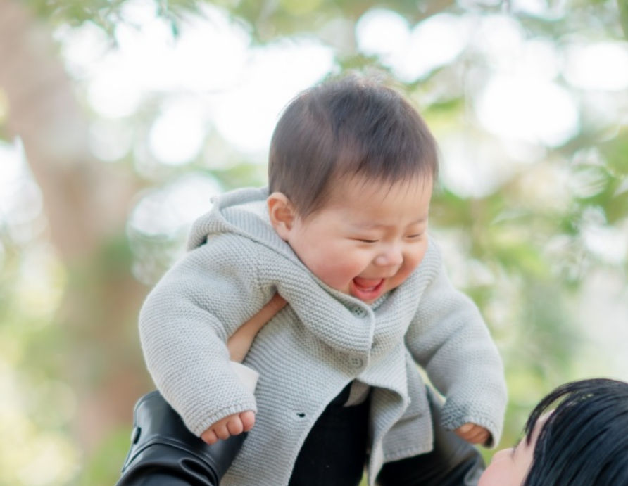 母に抱っこされ笑う赤ちゃん